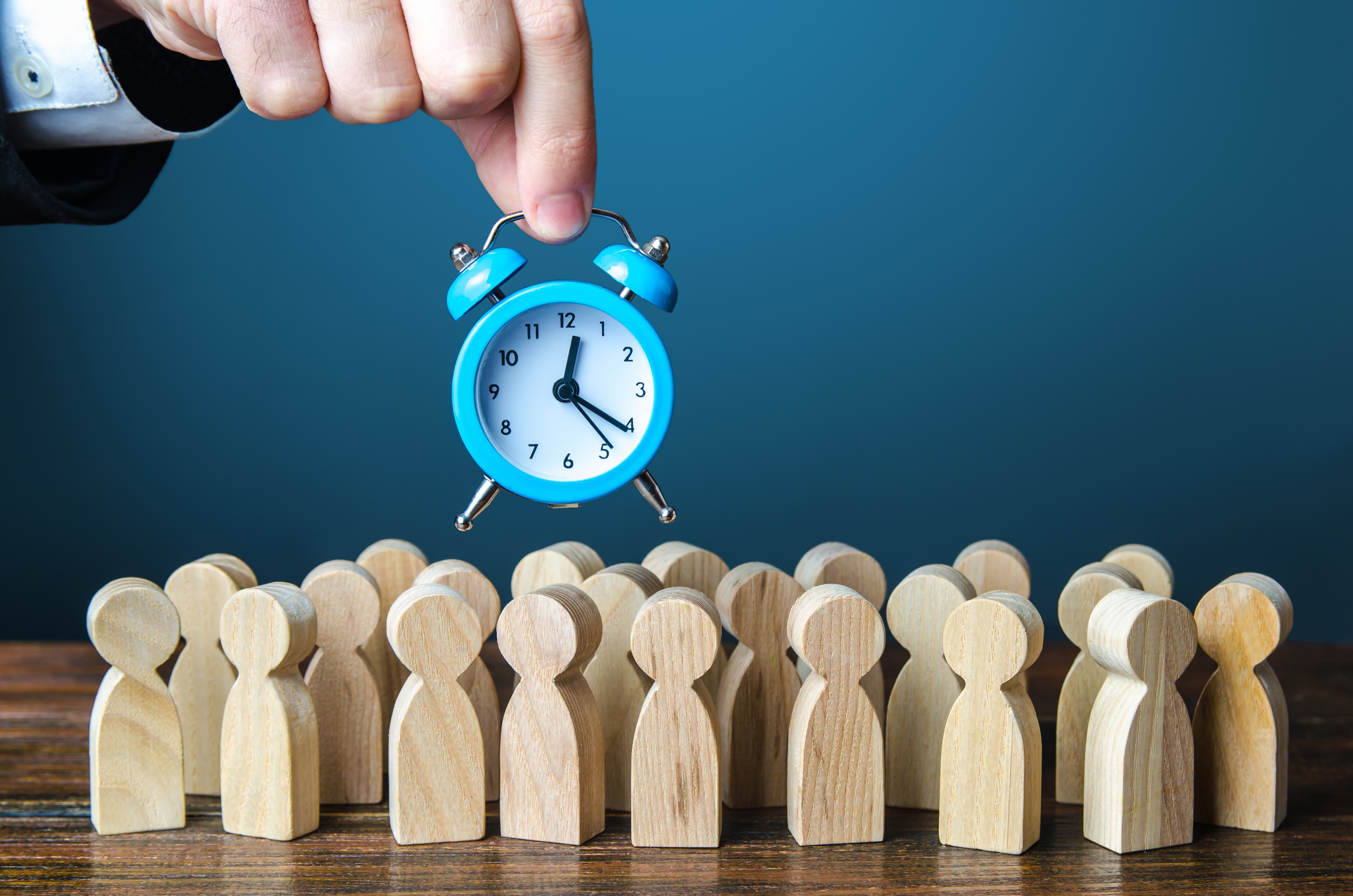 Alarm clock with wooden figures representing workforce time management